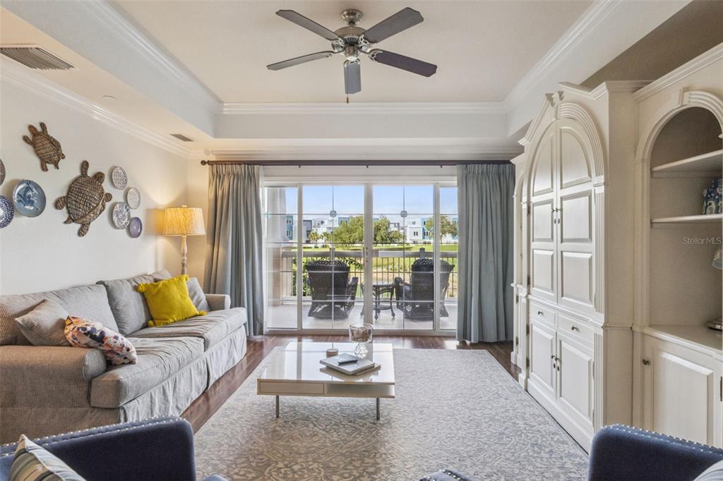A living room features a tray ceiling, a sofa, a white cabinet, and a balcony — 1112 SUNSET VIEW CIRCLE UNIT 203, KISSIMMEE, FL
