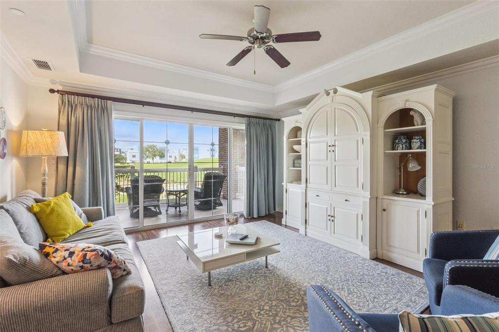 A living room features a white entertainment center, a gray sofa, and a balcony view — 1112 SUNSET VIEW CIRCLE UNIT 203, KISSIMMEE, FL
