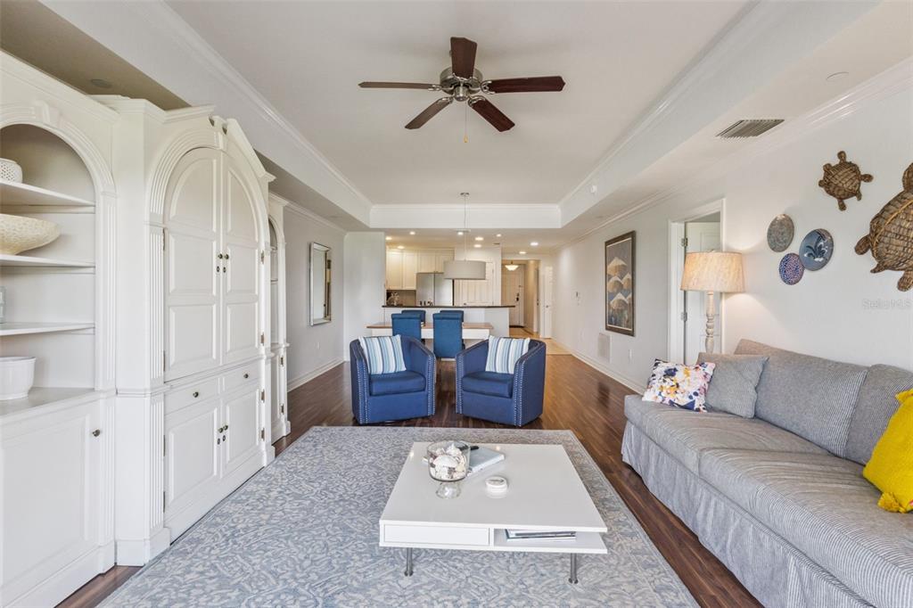A living room features a white cabinet, blue armchairs, a gray sofa, and hardwood floors — 1112 SUNSET VIEW CIRCLE UNIT 203, KISSIMMEE, FL