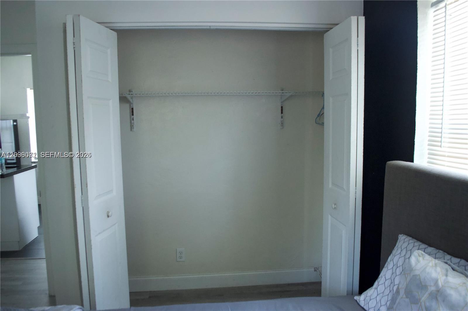 A bedroom closet with white bi-fold doors and a single wire shelving unit inside — 5530 N Miami Ave # 2, Miami FL 33127, MIAMI, FL