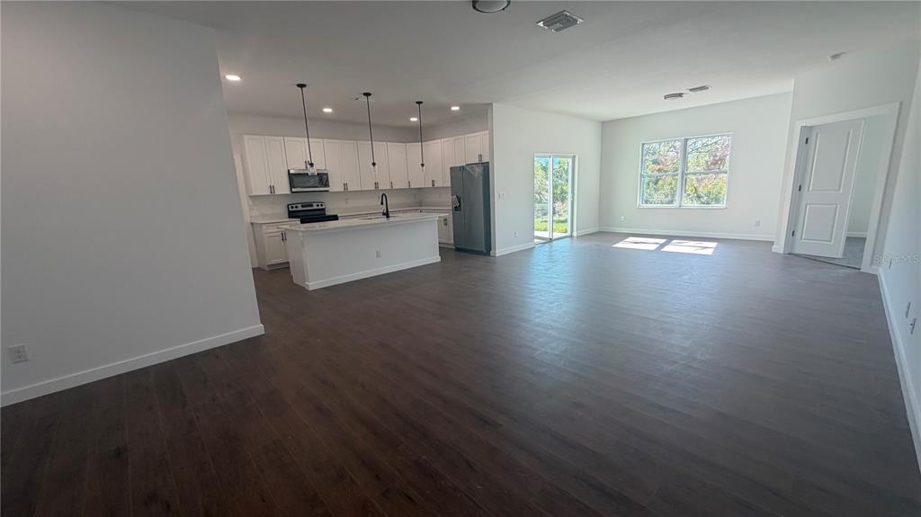 An open-concept kitchen and living area features white cabinetry, a center island, and dark flooring — 319 SPAULDING STREET, PORT CHARLOTTE, FL