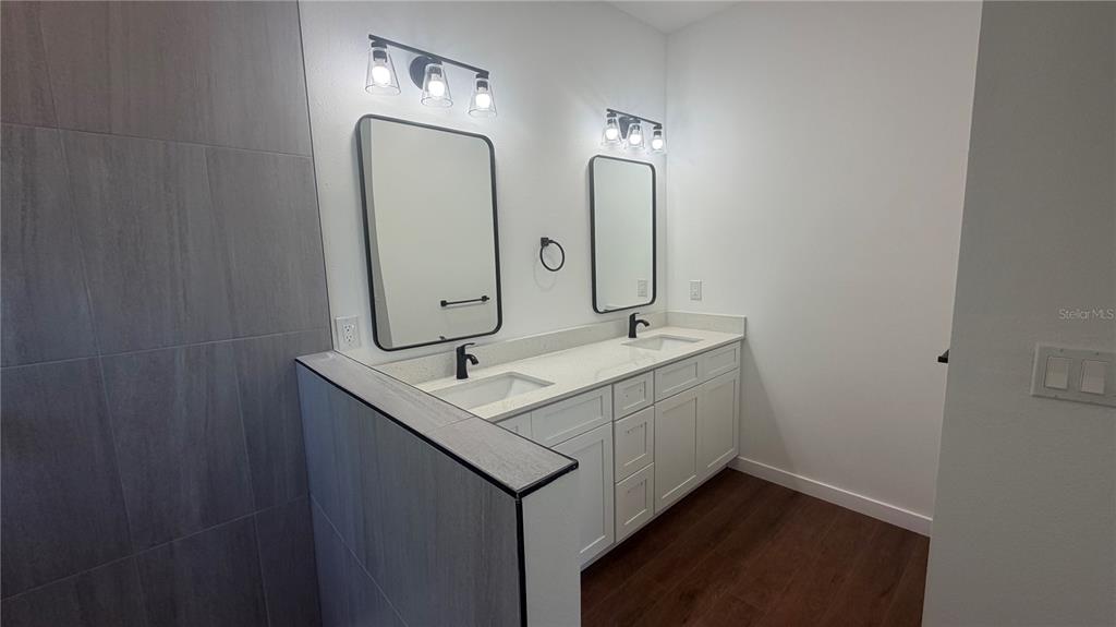 A modern bathroom features a double vanity with white cabinets and two rectangular mirrors — 319 SPAULDING STREET, PORT CHARLOTTE, FL