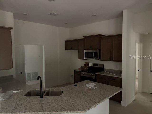 A kitchen features dark wood cabinets, granite countertops, a stainless steel microwave, and a sink — 13510 SW 64TH STREET ROAD, OCALA, FL