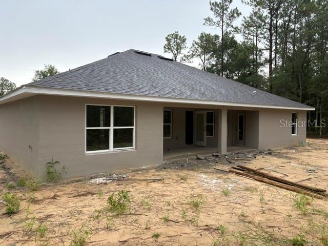 The exterior of a tan, single-story house with a gray shingled roof and sandy yard — 13510 SW 64TH STREET ROAD, OCALA, FL