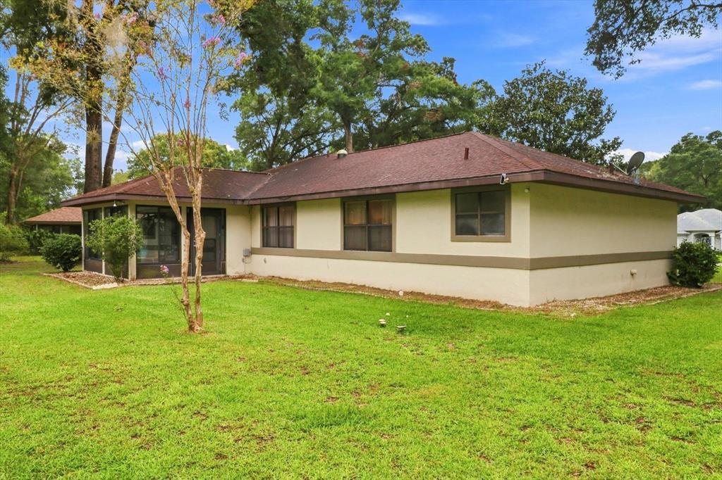 The exterior of a single-story house with a screened-in porch and a grassy backyard — 9251 SW 192ND COURT, DUNNELLON, FL