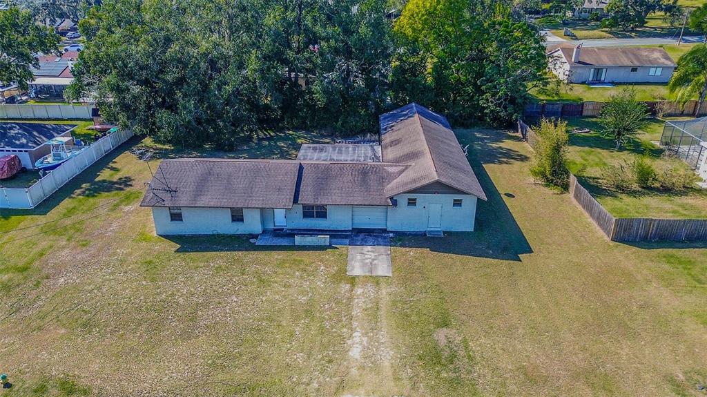 An aerial view of a single-story house with a brown roof and a dirt driveway — 11425 SUN ROAD, DADE CITY, FL