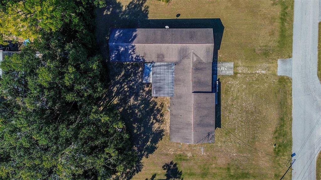 An aerial view shows an L-shaped house with a dark roof situated on a grassy lot — 11425 SUN ROAD, DADE CITY, FL