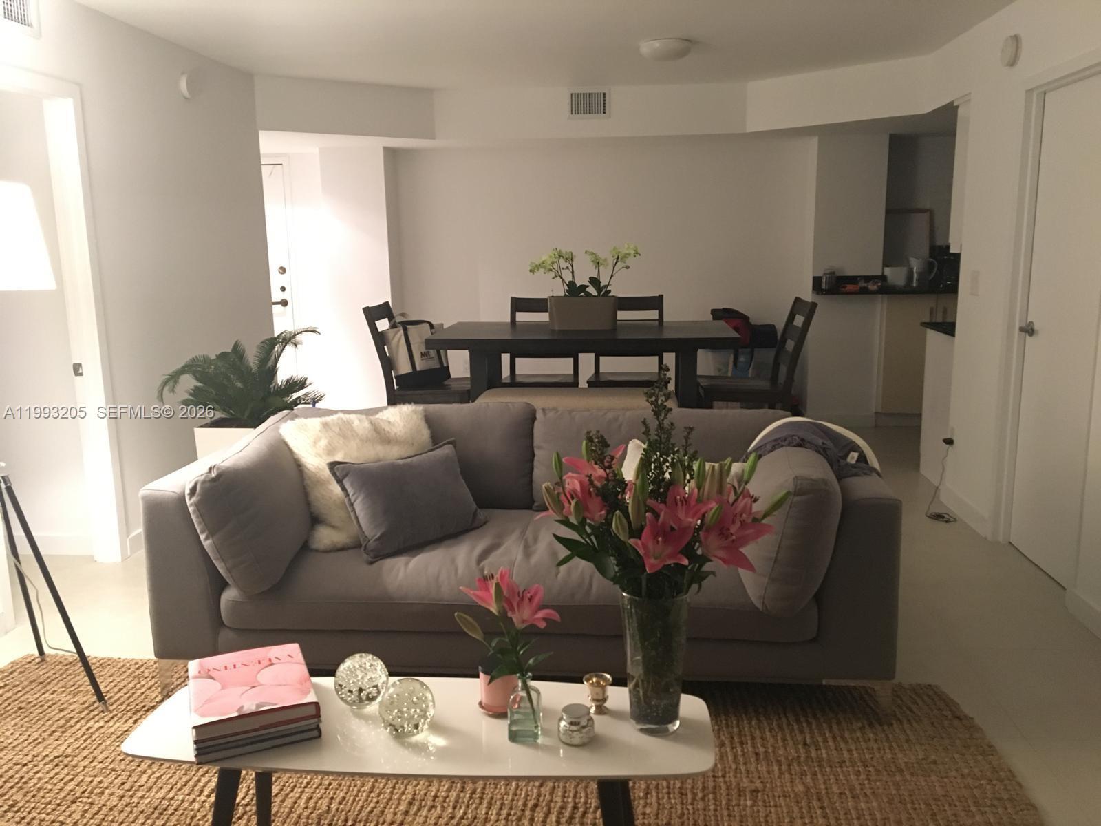 A living room with a grey sofa, white coffee table, and dining area in the background — 2333 Brickell Ave, Miami FL 33129, MIAMI, FL