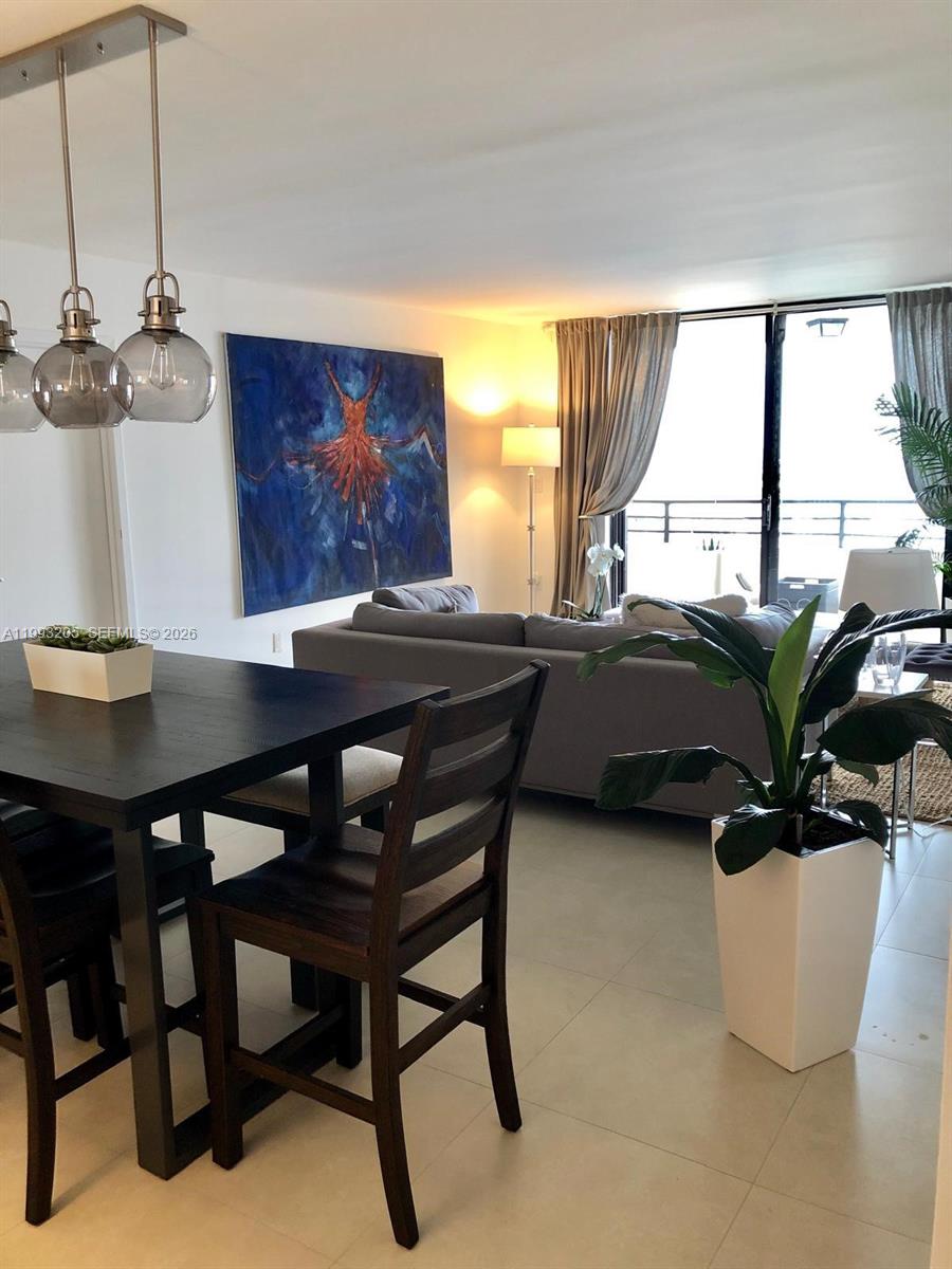 A dining area with a dark table and chairs opens into a living room with balcony access — 2333 Brickell Ave, Miami FL 33129, MIAMI, FL