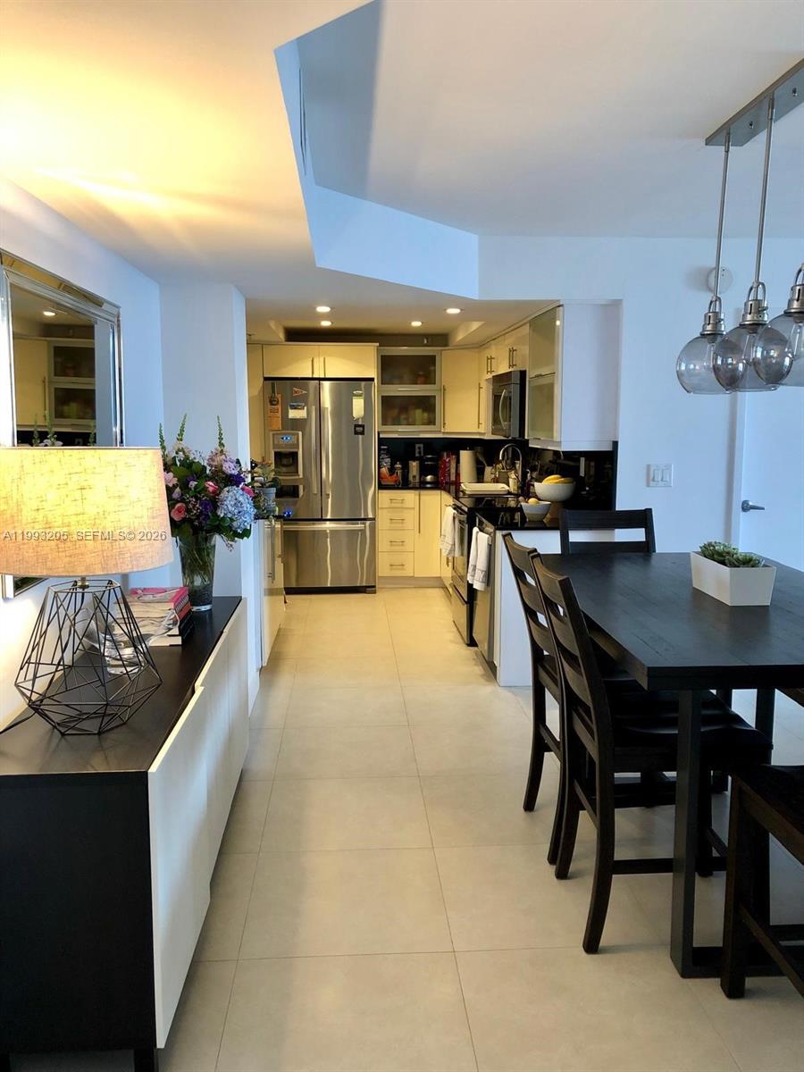 A dining area with a dark table leads into a kitchen with stainless steel appliances — 2333 Brickell Ave, Miami FL 33129, MIAMI, FL