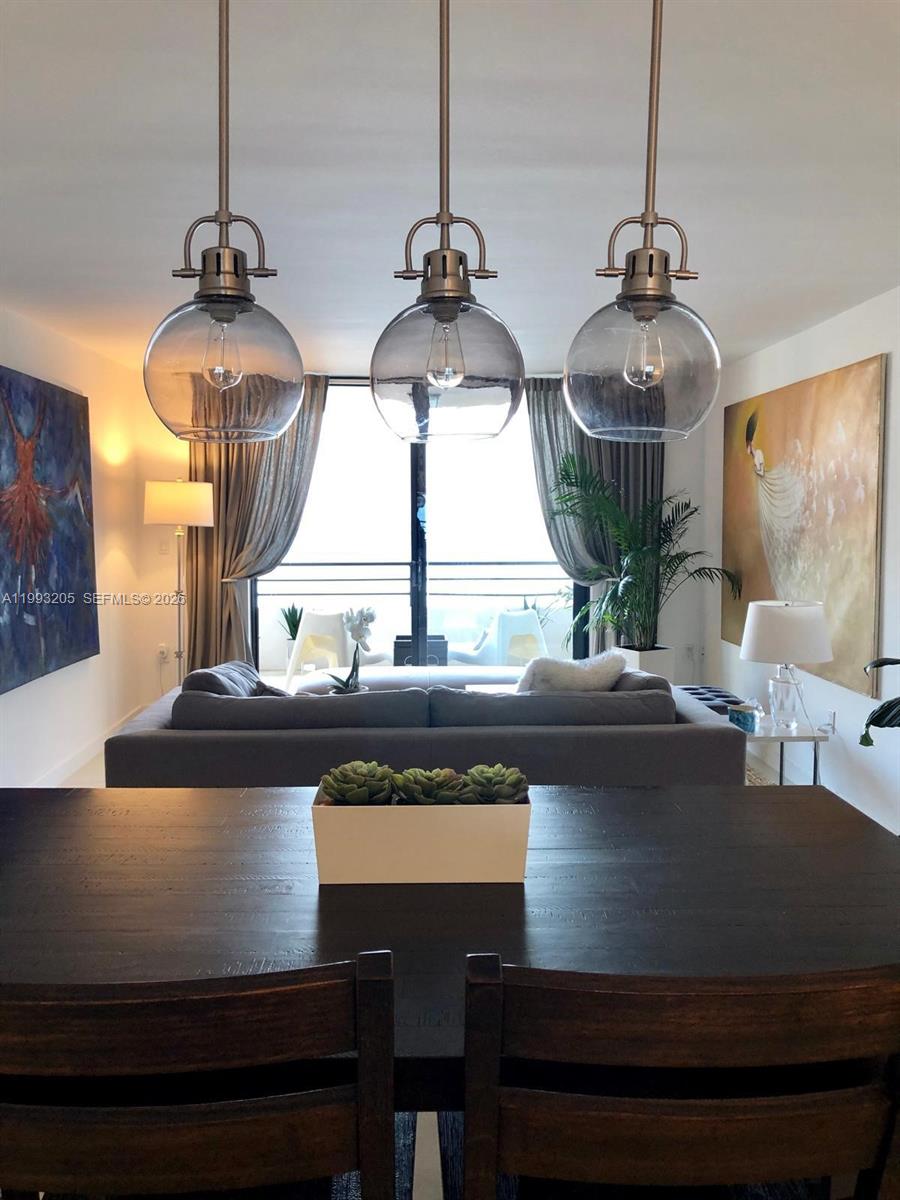 A dining area with a dark wooden table overlooks a living room and balcony — 2333 Brickell Ave, Miami FL 33129, MIAMI, FL