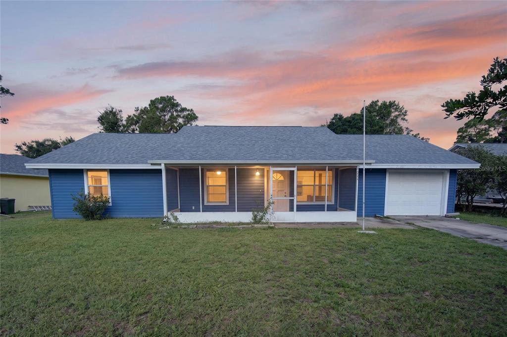 A single-story blue house with a screened front porch and a one-car garage — 3012 UMBRELLA TREE DRIVE, EDGEWATER, FL