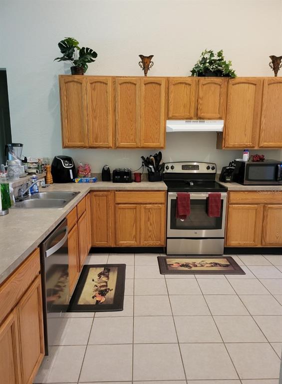 A kitchen features oak cabinets, stainless steel appliances, and light-colored tile flooring — 5419 OXFORD MANOR CIRCLE, LAKELAND, FL