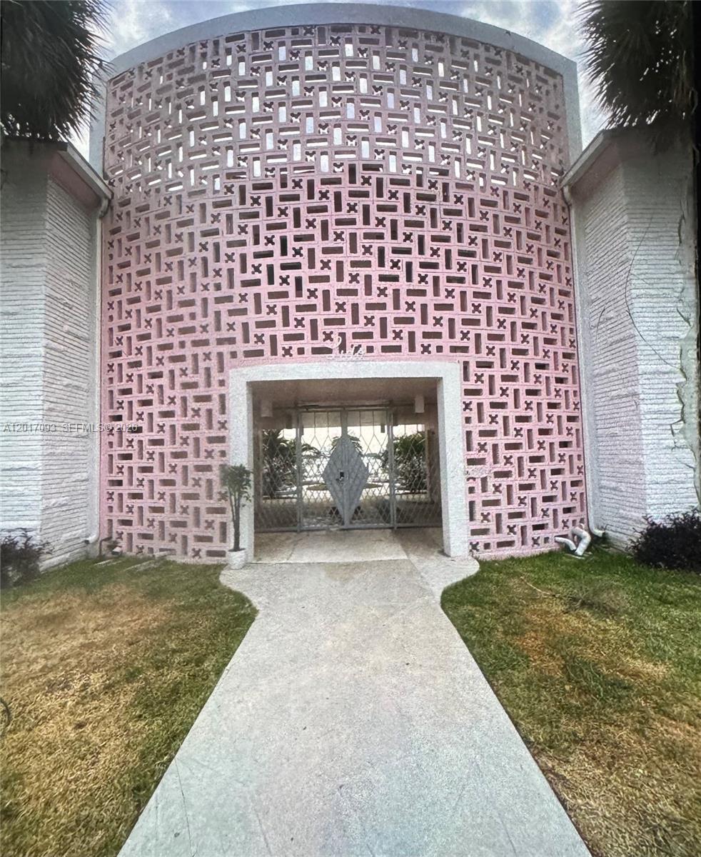A pink decorative concrete block facade frames the entrance to a gated walkway — NORTH BAY VILLAGE, FL