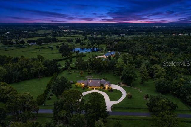 An aerial view shows a house with a curved driveway surrounded by trees and fields — 5950 SW 21ST AVENUE ROAD, OCALA, FL