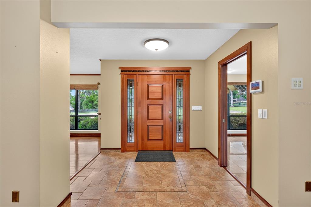 An entryway features a wood front door with sidelights, tile flooring, and beige walls — 5950 SW 21ST AVENUE ROAD, OCALA, FL