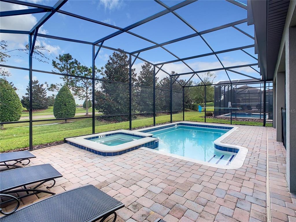 A screened-in patio features a swimming pool, a raised spa, and brick paver decking — 1305 DIVOT WAY, DAVENPORT, FL