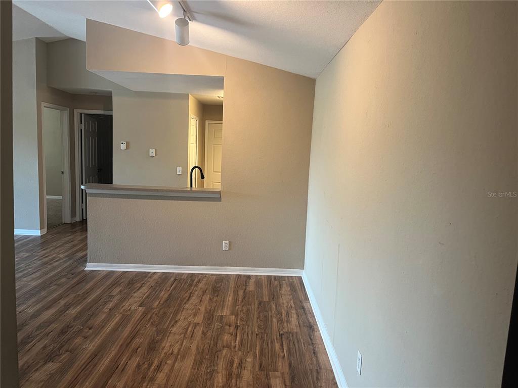 A view of a living area with wood-look flooring, a breakfast bar, and vaulted ceilings — 7511 SEURAT STREET UNIT 10304, ORLANDO, FL