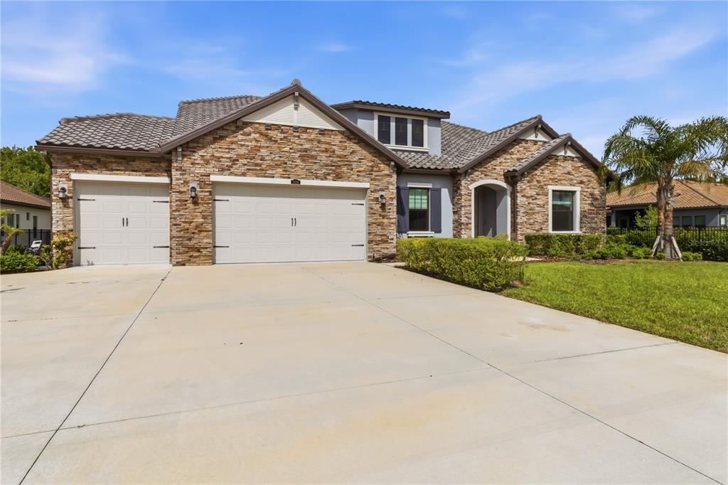 A single-story house with a stone facade, a three-car garage, and a concrete driveway — 3018 CORDOBA RANCH BOULEVARD, LUTZ, FL