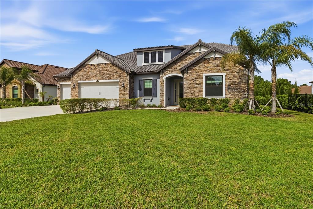 A single-story house with a stone facade, a two-car garage, and a manicured front lawn — 3018 CORDOBA RANCH BOULEVARD, LUTZ, FL