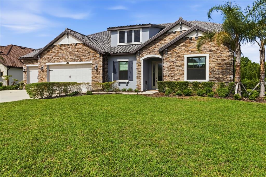 A single-story house with a stone facade, a two-car garage, and a manicured front lawn — 3018 CORDOBA RANCH BOULEVARD, LUTZ, FL