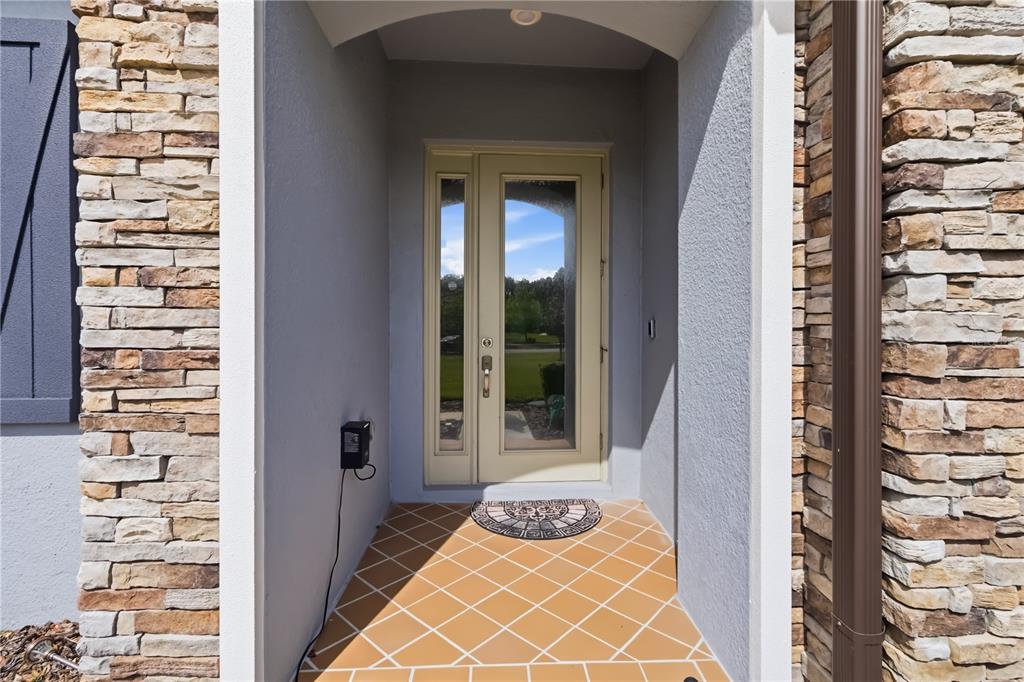 A front entryway features a light-colored door, stone siding, and orange tiled flooring — 3018 CORDOBA RANCH BOULEVARD, LUTZ, FL
