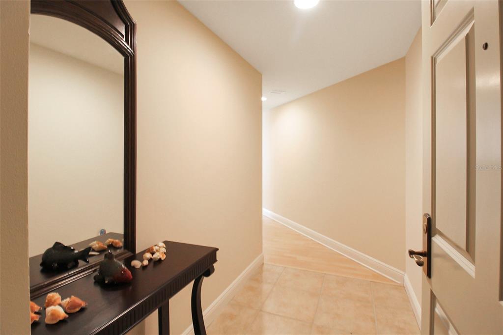 A hallway features a console table with a mirror, tile flooring, and light-colored walls — 800 N TAMIAMI TRAIL UNIT 806, SARASOTA, FL