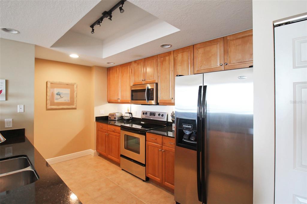 A kitchen features light wood cabinets, stainless steel appliances, and dark countertops — 800 N TAMIAMI TRAIL UNIT 806, SARASOTA, FL
