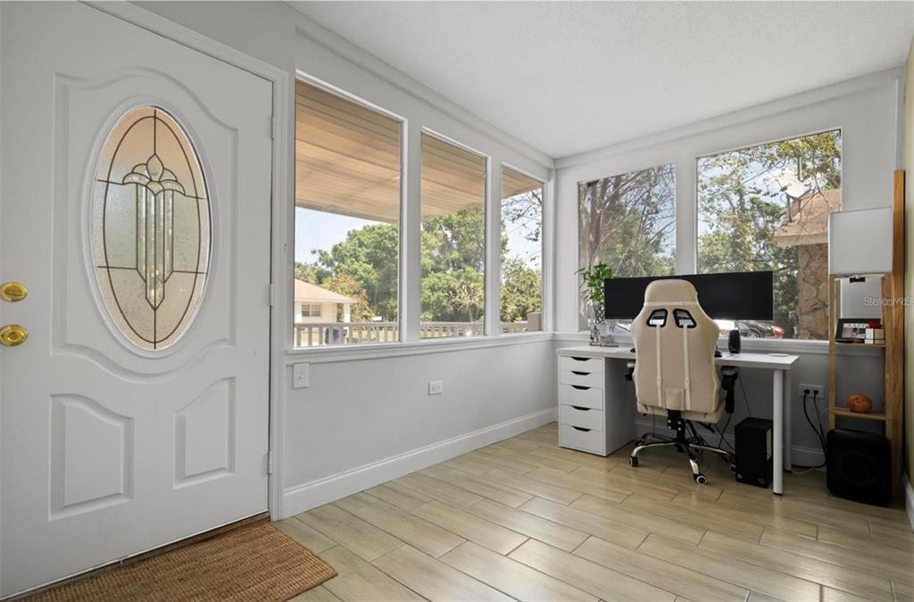 A bright home office features a white desk, gaming chair, and large windows with tile flooring — 2821 MARCONI STREET, TAMPA, FL