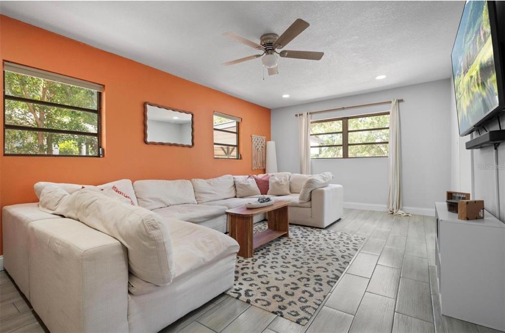 A living room features an orange accent wall, white sectional sofa, and light tile flooring — 2821 MARCONI STREET, TAMPA, FL