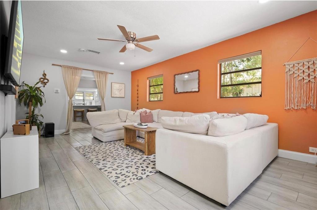 A living room features a large white sectional sofa, orange accent wall, and tiled floors — 2821 MARCONI STREET, TAMPA, FL