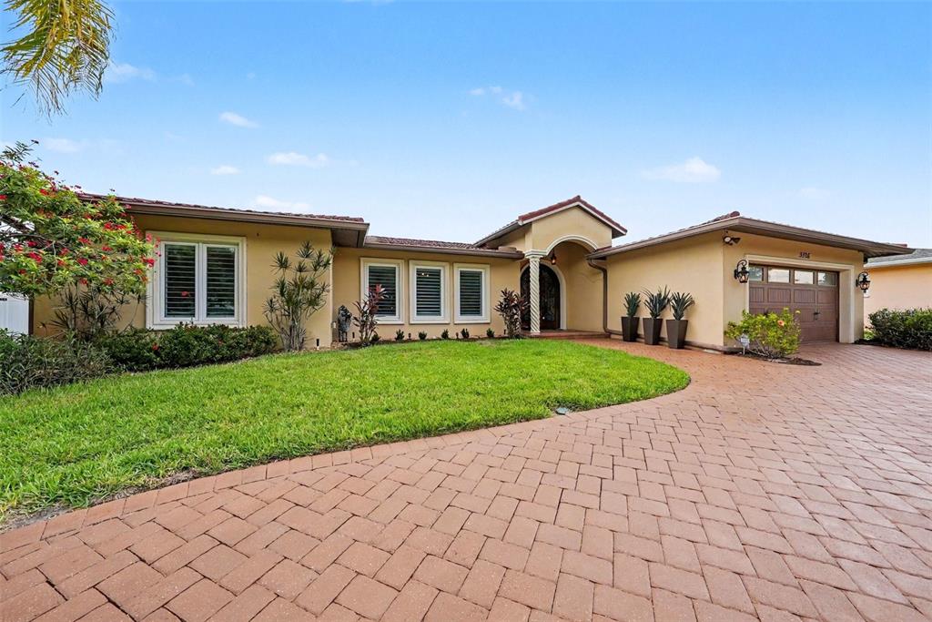 A single-story house with a tan stucco exterior, a tiled roof, and a brick driveway — 3316 SAN JOSE STREET, CLEARWATER, FL