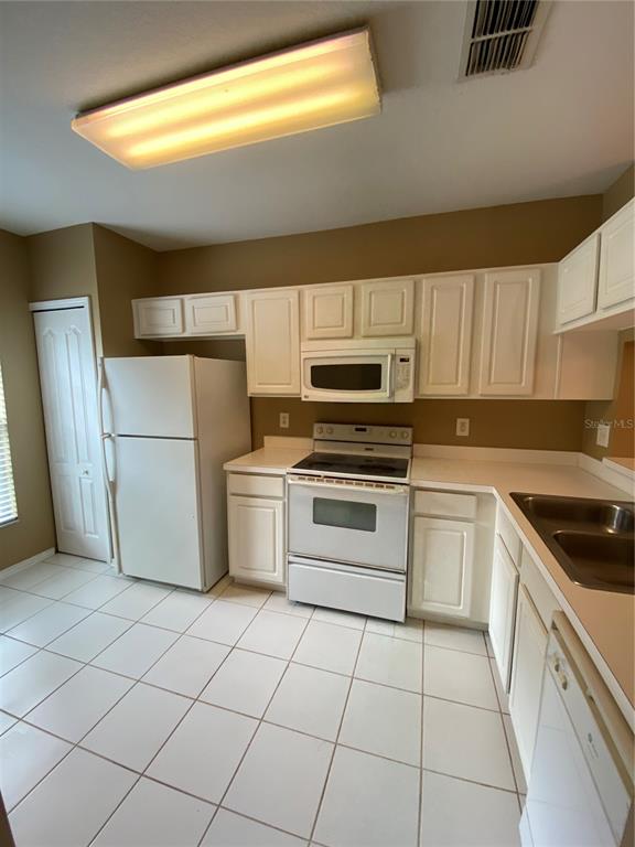 A kitchen with white cabinets, white appliances, and light-colored tile flooring — 1309 THROCKMORTON DRIVE, WESLEY CHAPEL, FL