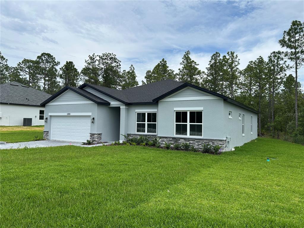A single-story house with light gray stucco, a stone veneer base, and a white garage — 13190 ENGLISH FIR COURT, BROOKSVILLE, FL