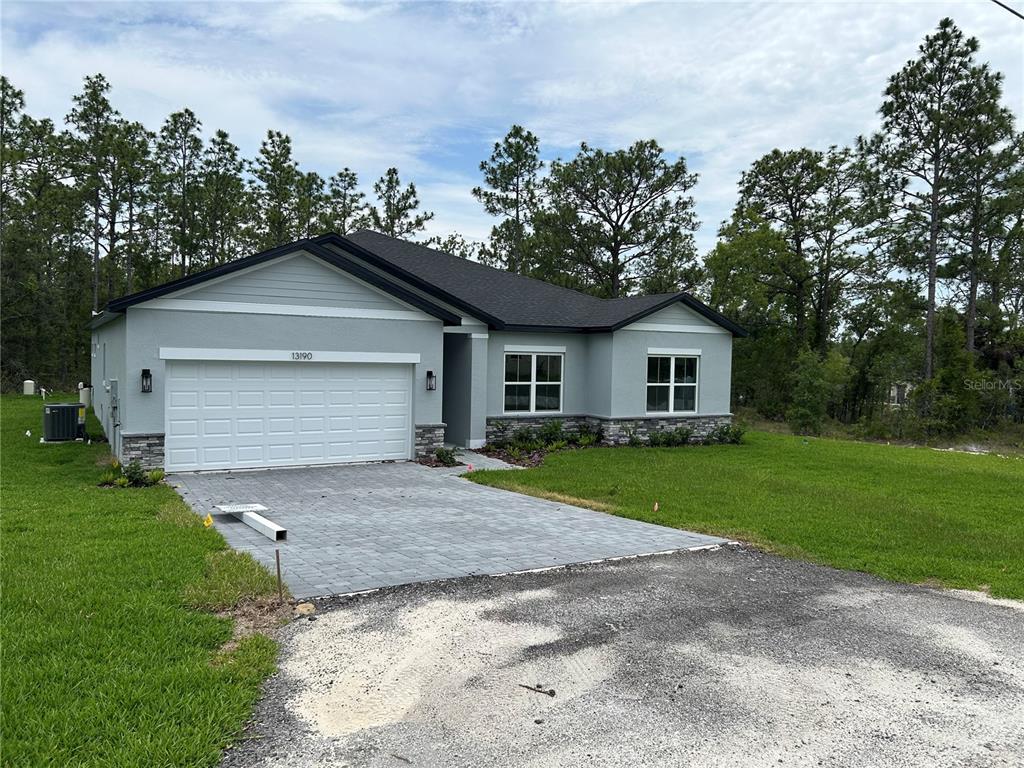 A single-story house with a gray exterior, stone accents, and a paved driveway — 13190 ENGLISH FIR COURT, BROOKSVILLE, FL