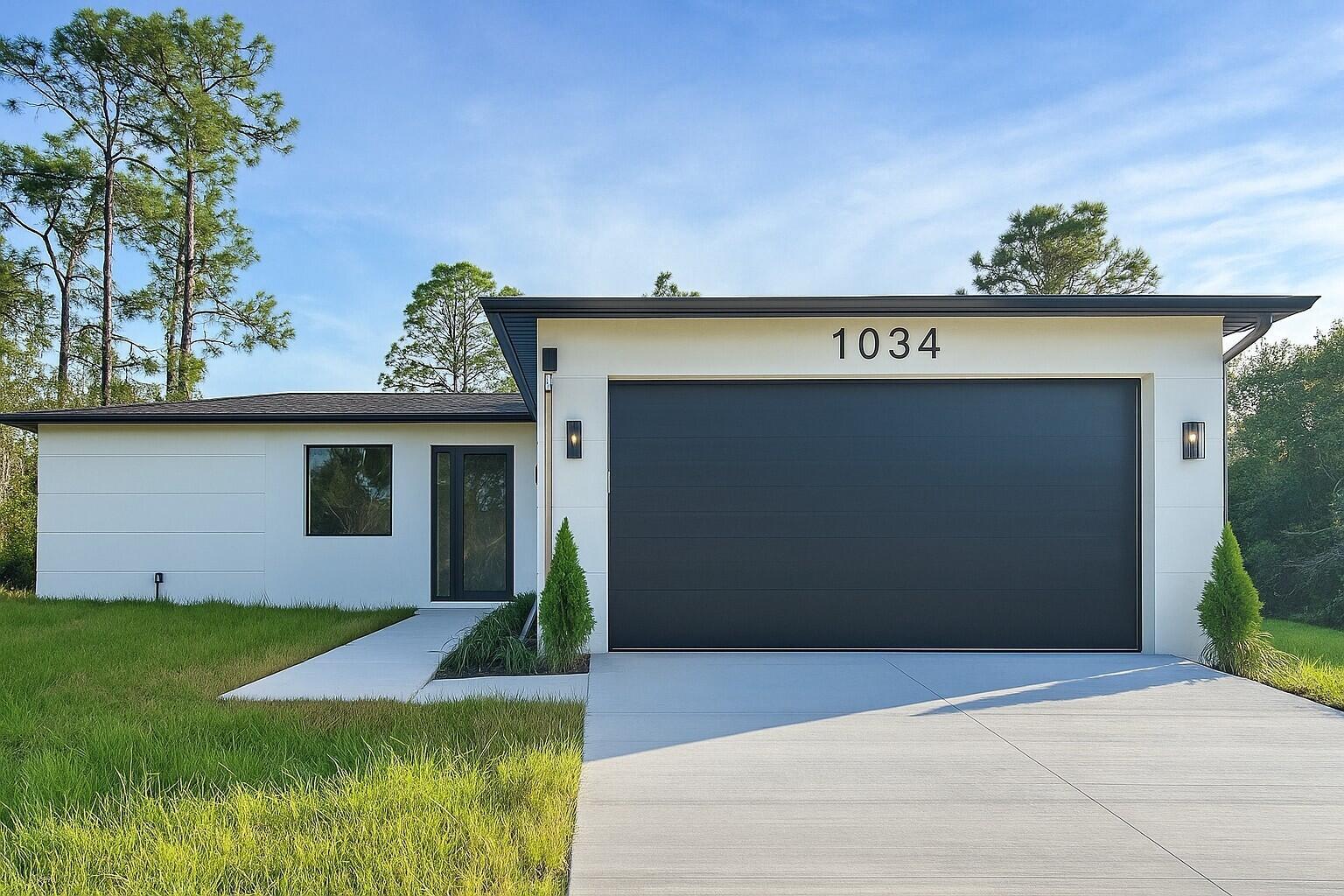 A modern single-story house with a white exterior, black garage door, and a concrete driveway — 1034 E Alcalde St Street E, Lehigh Acres FL 33974, LEHIGH ACRES, FL