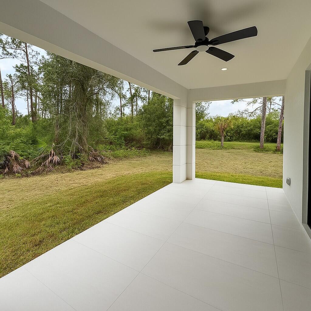 A covered patio with white tile flooring, a black ceiling fan, and a grassy backyard — 1034 E Alcalde St Street E, Lehigh Acres FL 33974, LEHIGH ACRES, FL