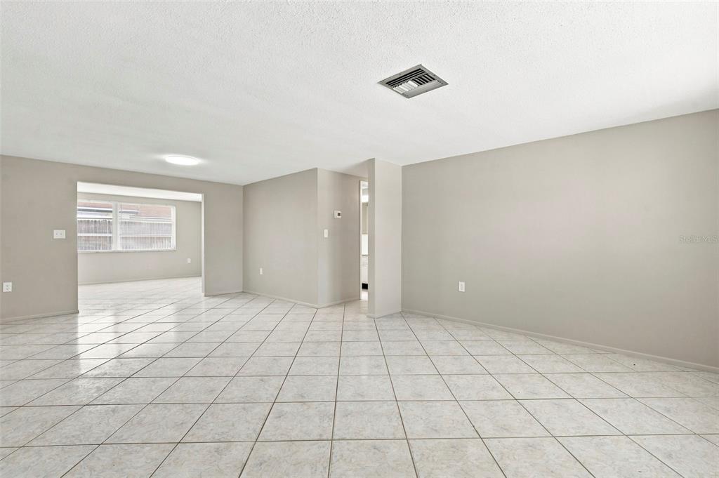 An empty room with light-colored tile flooring, beige walls, and a recessed ceiling vent — 8936 WINDSONG LANE, PORT RICHEY, FL