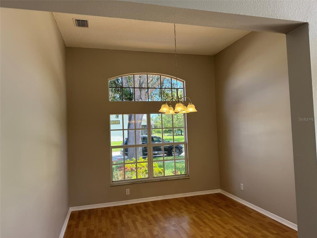 A dining room with high ceilings, wood flooring, a chandelier, and a large arched window — 10104 BEEFMASTER COURT, NEW PORT RICHEY, FL