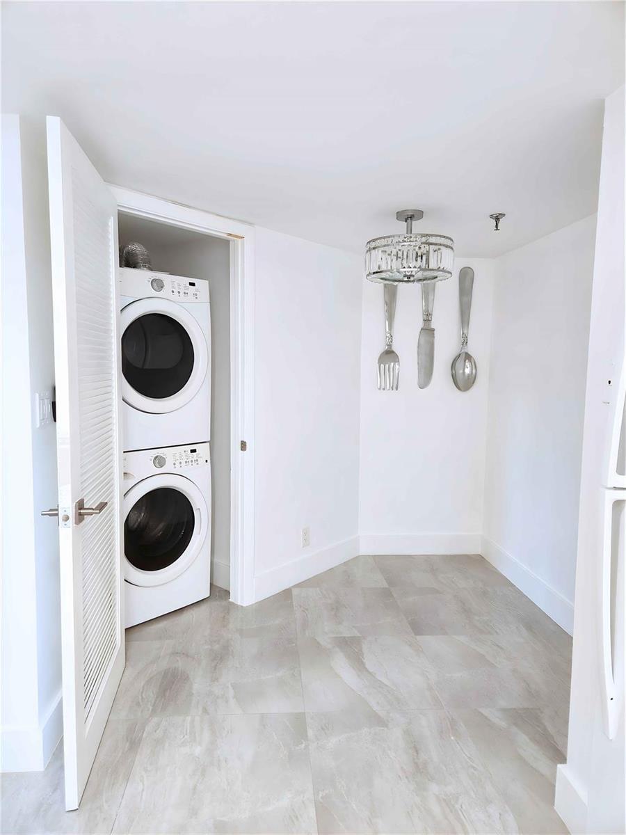 A laundry closet with a stacked washer and dryer sits beside a dining area with decor — 6463 La Costa Drive # 301, Boca Raton FL 33433, BOCA RATON, FL