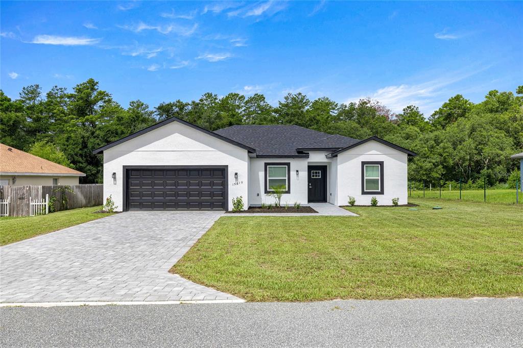 A white single-story house with a black garage door and roof sits on a grassy lot — 15610 SW 28TH AVENUE ROAD, OCALA, FL