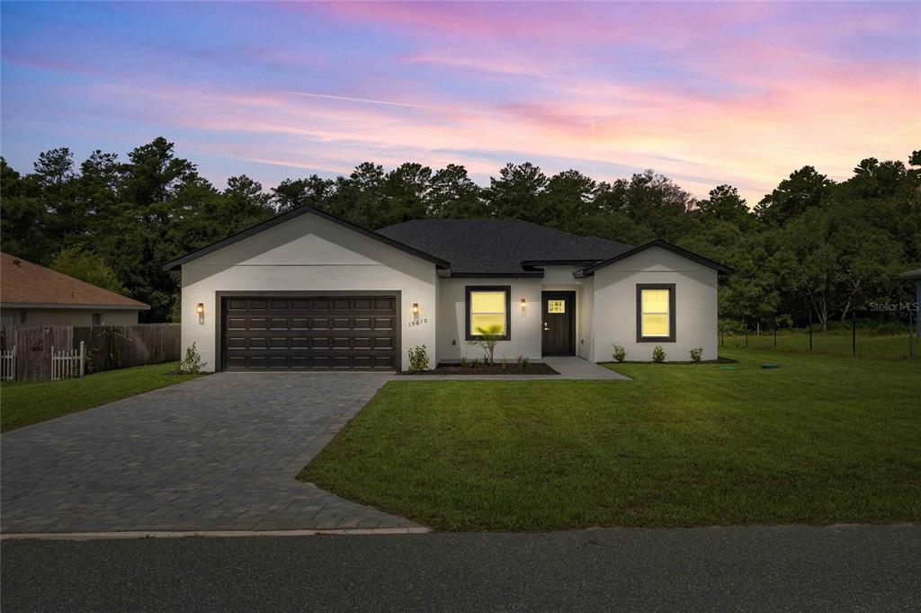A single-story house with a white stucco exterior, dark trim, and a paved driveway — 15610 SW 28TH AVENUE ROAD, OCALA, FL