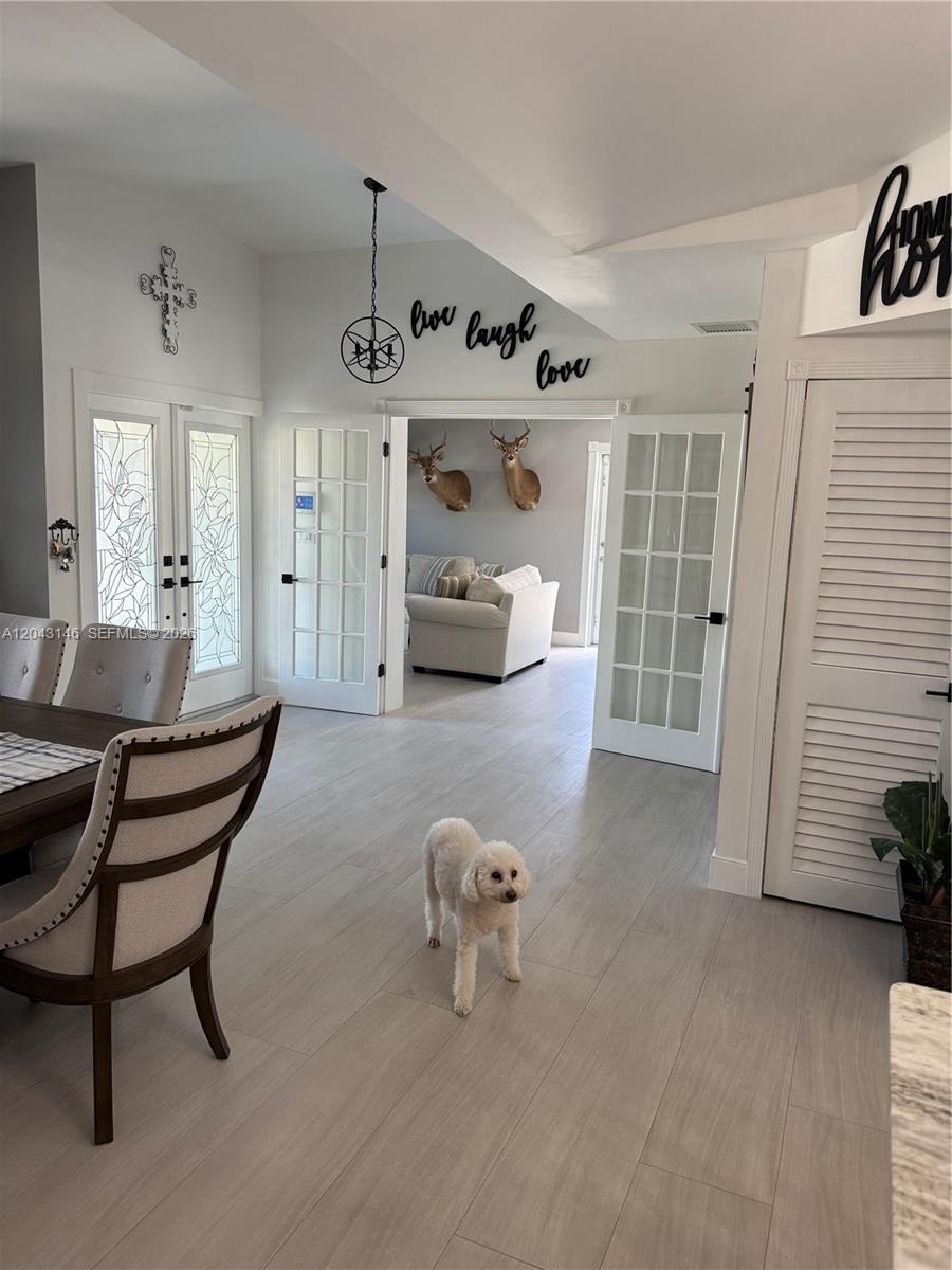 An entryway features light wood-look flooring, French doors, and a mirror with barn-door hardware — 4947 SW 143rd Ave, Miami FL 33175, MIAMI, FL