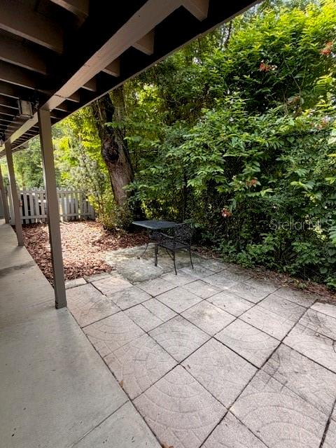 A covered concrete patio overlooks a mulched yard with a small table and chairs — 250 CEDARWOOD DRIVE, MAITLAND, FL