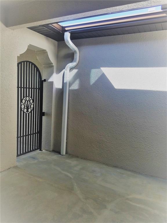 A white downspout runs down a gray stucco wall next to a decorative metal gate — 8504 MAGNIFICENT LANE, GROVELAND, FL
