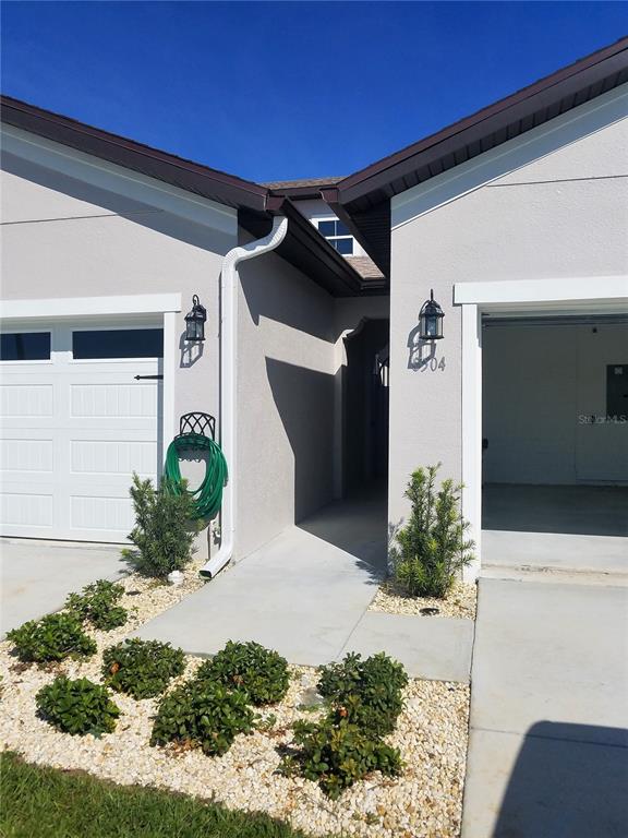 The exterior of a house features two garage doors, a central entryway, and landscaped gravel beds — 8504 MAGNIFICENT LANE, GROVELAND, FL