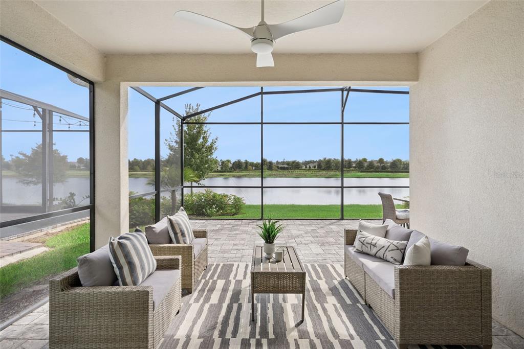 A screened-in patio features wicker furniture, a patterned rug, and a view of a lake — 2499 CLIFF WAY, ST CLOUD, FL