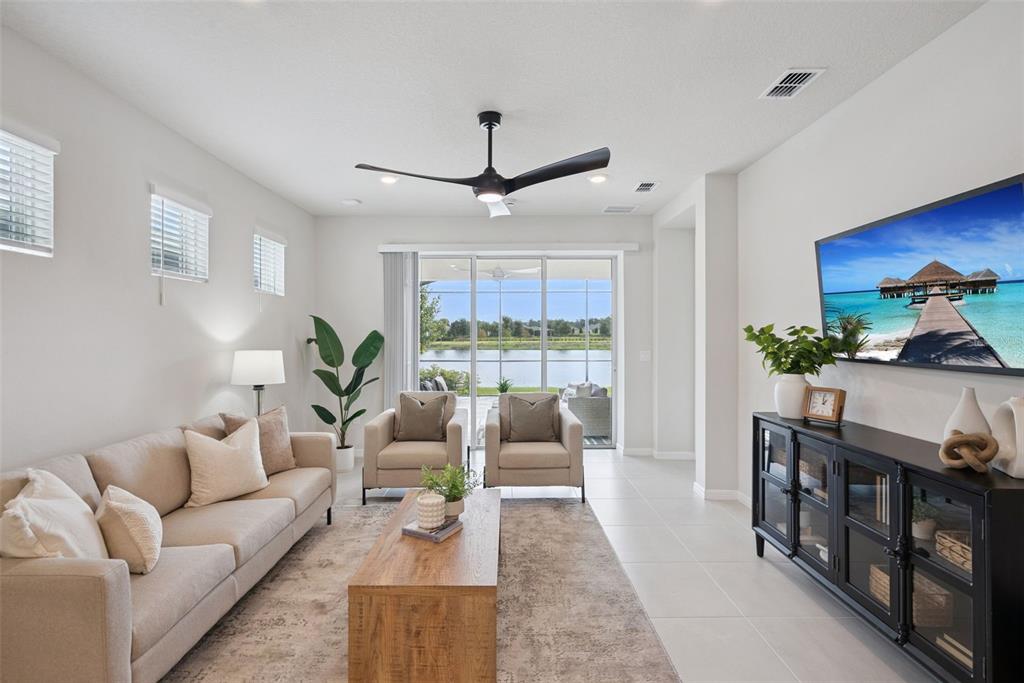 A living room features a beige sofa, two armchairs, a wooden coffee table, and lake views — 2499 CLIFF WAY, ST CLOUD, FL