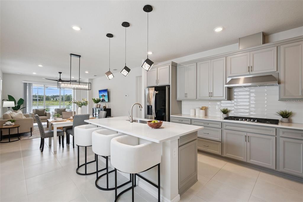 A modern kitchen with gray cabinets, white countertops, and an island with three white stools — 2499 CLIFF WAY, ST CLOUD, FL