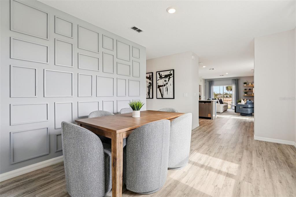 A dining area features a wood table, grey upholstered chairs, and a paneled accent wall — 4129 GIORGIO DRIVE, WINTER HAVEN, FL